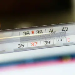 Dłoń trzyma termometr, na którym widać 37 stopni Celsjusza. Czy to początek febry?