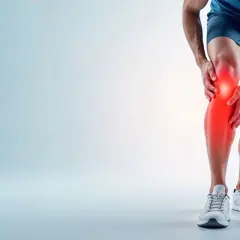 Mężczyzna trzyma się za nogę, odczuwając ostry **ból nogi pod kolanem**. Czerwony obszar podkreśla problem.