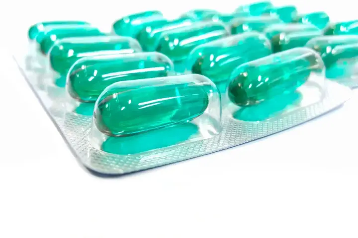 Blister opakowania z zielonymi kapsułkami, które mogą być lekiem **Inflanor Max**.