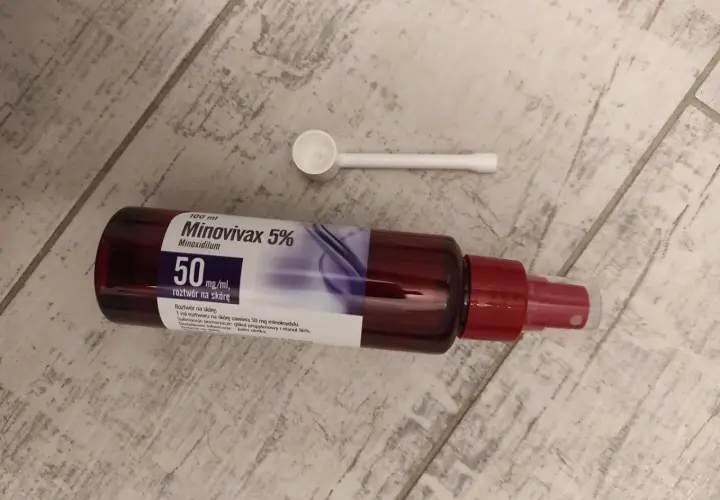 Butelka Minovivax 5% z aplikatorem na drewnianym tle. Preparat na porost włosów.