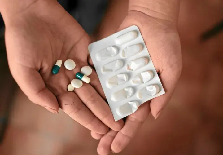 Dłonie trzymające tabletki i blister. Jedna z nich zawiera leki, które mogą być **inhibitory pompy protonowej**, stosowane w leczeniu problemów żołądkowych.