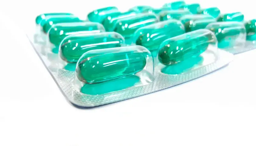 Blister opakowania z zielonymi kapsułkami, które mogą być lekiem **Inflanor Max**.