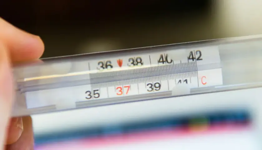 Dłoń trzyma termometr, na którym widać 37 stopni Celsjusza. Czy to początek febry?
