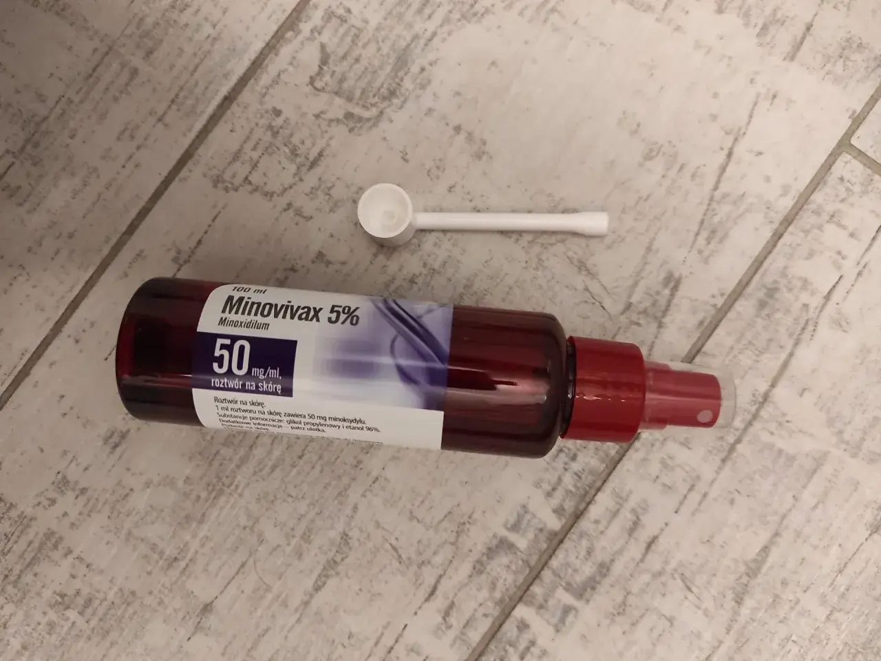 Butelka Minovivax 5% z aplikatorem na drewnianym tle. Preparat na porost włosów.